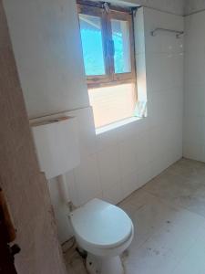 Un baño con inodoro blanco y ventana. en Stay house, en Bhopal