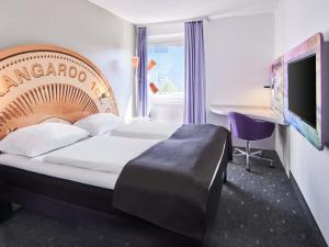 a hotel room with a bed and a desk and a tv at B&B Hotel Offenbach-Kaiserlei in Offenbach