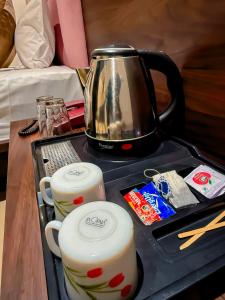 a tea kettle and cups on a tray on a table at Kings Executive and Restaurant in Tuljapur