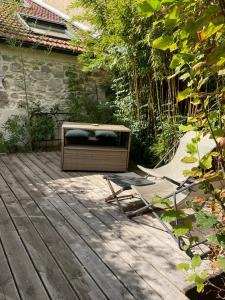 una terraza de madera con un banco y una silla. en Le Jardin de LaCoste, en Narbona
