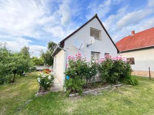 a white house with flowers in a yard at János Nyaraló in Balatonmáriafürdő