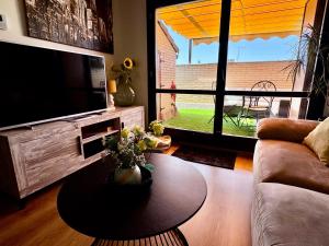 a living room with a couch and a table and a television at Ático Guara&Pirineos in Huesca