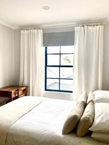 a bedroom with a white bed with a window at Foam House in Bloubergstrand