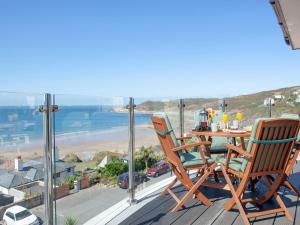 einen Tisch und Stühle auf einem Balkon mit Blick auf den Strand in der Unterkunft Soft Sands - Cottage in Woolacombe