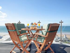 einen Holztisch und Stühle auf einer Terrasse mit Strand in der Unterkunft Soft Sands - Cottage in Woolacombe