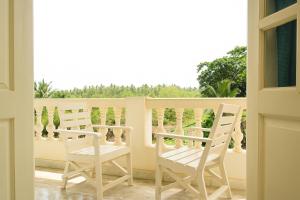 a balcony with two white chairs and a window at Sandeep Gurung Homes Stay in Calangute +3 photos