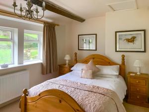 a bedroom with a bed and two windows at Royds Hall Cottage in Keighley