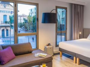 a hotel room with a bed and a large window at Novotel Suites Malaga Centro in Málaga