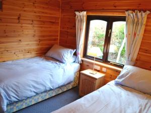 Un dormitorio con dos camas en una cabaña de madera. en Glenmore Lodge, en Keswick