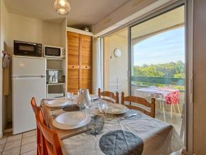 a dining room with a table and a kitchen with a window at T2 lumineux pour 2, animaux admis, parking, WiFi - FR-1-841-47 in Barbotan-les-Thermes