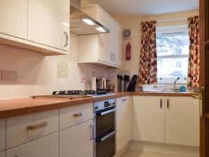 a kitchen with white cabinets and a stove top oven at 1 Lonsdale House in Keswick