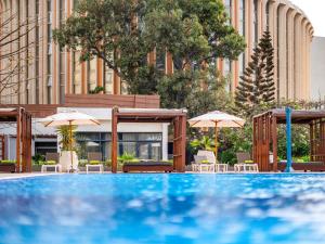 una gran piscina con sombrillas y un edificio en Ibis Styles Dakar, en Dakar