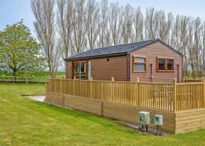 a small wooden house with a fence and a yard at Cleveland Hills View Holiday Park in Middleton upon Leven +44 photos