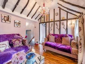 a living room with purple couches and a chandelier at Brittons Hill Cottage in Wavehorne