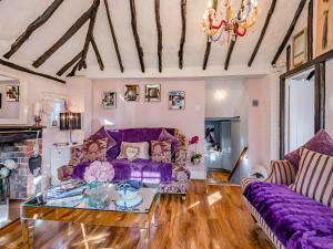 a living room with purple couches and a glass table at Brittons Hill Cottage in Wavehorne