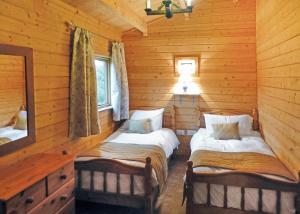 a bedroom with two beds in a log cabin at Goodiford Mill Lakes in Kentisbeare