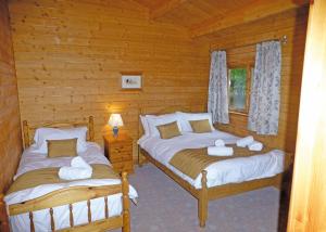 a bedroom with two beds in a log cabin at Goodiford Mill Lakes in Kentisbeare +16 photos