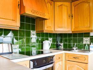a kitchen with wooden cabinets and green tiles at The Chalet - Uk34712 in Reighton +10 photos