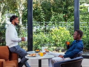 two men sitting around a table drinking coffee at Aparthotel Adagio La Défense Le Parc in Courbevoie +61 photos