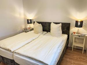 a bedroom with a bed with white sheets and two lamps at Apartment Müritz Ferienpark Röbel-32 by Interhome in Marienfelde