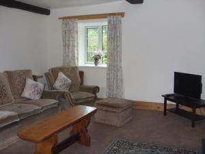a living room with a couch and a tv at East Hook Holiday Cottages - Daisy Cottage in Okehampton