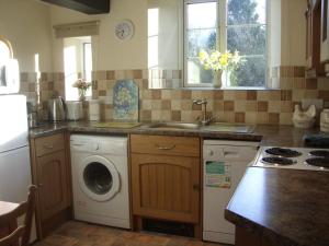 a kitchen with a sink and a washing machine at East Hook Holiday Cottages - Daisy Cottage in Okehampton +9 photos