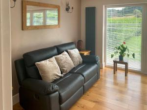 a black leather couch in a living room with a window at Catcleugh Bridge View in Kielder