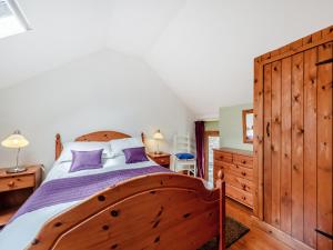 a bedroom with a large wooden bed with purple pillows at Ty Nant-Oxl in Gwynfe