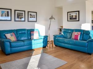 two blue leather couches in a living room at The Longhouse At Threave in Castle Douglas