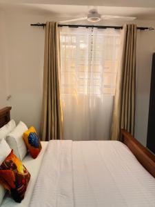 a bedroom with a white bed and a window at Pamito Sunny Paradise in Diani in Diani Beach