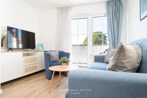 een woonkamer met een blauwe bank en een tv bij Nautic W21 in Laboe