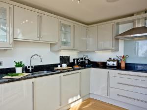 eine weiße Küche mit weißen Schränken und einer Spüle in der Unterkunft Quantock Lodge in Chillington