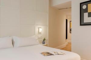a bedroom with a white bed with a book on it at Room Mate Cosmo - City Centre, Valencia in Valencia