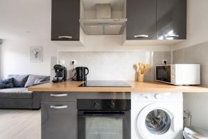 a kitchen with a stove top oven next to a microwave at Le Nid du Beffroi - Studio centre Doullens in Doullens