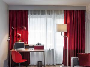 a room with a desk with a computer and red curtains at Aparthotel Adagio Paris Bercy Village in Paris +91 photos