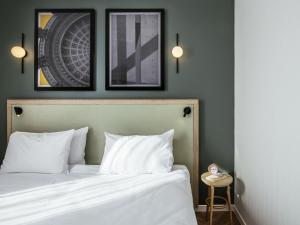 a bedroom with a bed with two pictures on the wall at Aparthotel Adagio Paris Buttes Chaumont in Paris