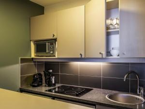 a kitchen with a stove and a microwave at Aparthotel Adagio Paris Buttes Chaumont in Paris