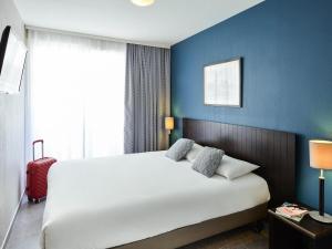 a bedroom with a large white bed with a blue wall at Aparthotel Adagio Monaco Monte Cristo in Beausoleil +55 photos