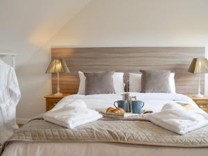 Una cama con toallas y una bandeja de comida. en Horseshoe Cottage, en Fife
