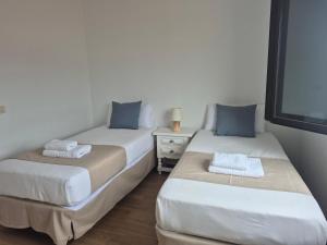 two beds in a small room with a night stand at Sabbia Suites Casa Vera in Teguise