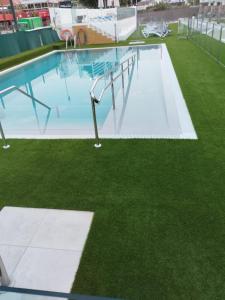 an empty swimming pool with grass in a building at Apartamentos Florida Gran Canaria Adults Only in Puerto Rico de Gran Canaria