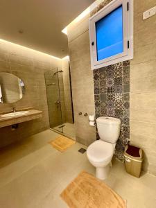 La salle de bains est pourvue de toilettes et d'une télévision murale. dans l'établissement Royal Nile Villa - Luxury Nile Sky Penthouse 1, à Al Aqālitah