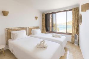 two beds in a room with a large window at Abora Mar - Beach Apartment in Patalavaca