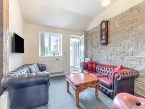 Una sala de estar con muebles de cuero y una pared de ladrillo. en Greystones Nawab Annex A, en Monyash