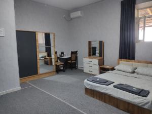 a bedroom with a bed and a desk and a table at Osiyo in Olmaliq