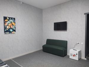 a room with a green chair and a television at Osiyo in Olmaliq