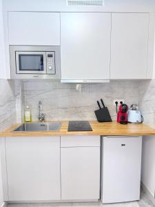 Una cocina blanca con fregadero y microondas. en Elegant and Comfortable Studio Jouvenet, en París