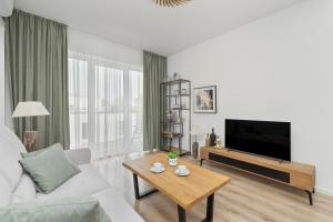 a living room with a couch and a tv and a table at Stela Water Side Apartment - Swimming Pool & Sauna by Renters Prestige in Dziwnów