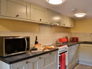a kitchen with white cabinets and a microwave at Mill Cottage in Peterchurch