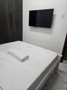 Una cama con un televisor en una pared blanca. en Nyali DSQ No Kitchenette, en Nyali